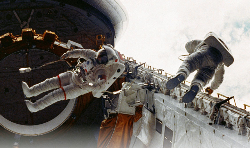 two astronauts working on the outside of their spacecraft