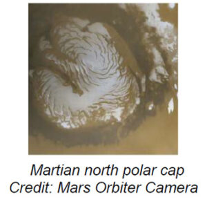 The image shows the north pole of Mars, characterized by a large, swirling ice cap. The ice cap is predominantly white with intricate, spiraling patterns that resemble a whirlpool, set against a brownish-red Martian surface. The boundaries of the ice cap show a stark contrast between the bright white ice and the darker surface of the planet. The surrounding terrain appears rough and uneven, with patches of lighter shades indicating possible frost or additional ice formations.