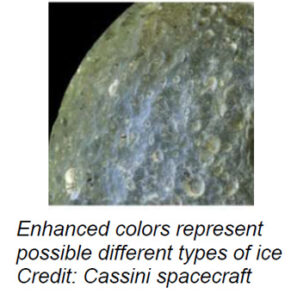 The image shows a detailed close-up view of the surface of Mimas, one of Saturn’s moons. The surface is textured and cratered, predominantly in shades of gray and subtle hints of blue and green. Numerous craters of various sizes are scattered across the visible surface, giving it a rugged appearance. The craters create shadows and highlights, contributing to the uneven texture.