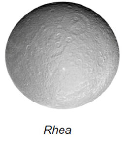 The image depicts a detailed view of a celestial body, identified as Rhea, one of Saturn's moons. It is a spherical object with a lightly textured, gray surface that is peppered with numerous craters of various sizes. The craters appear to cover much of the surface, with the larger ones more pronounced, casting subtle shadows indicative of depth. The image captures the moon in full view against a white background, highlighting its rough, cratered terrain.
