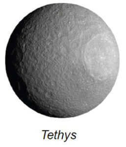 The image showcases Tethys, one of Saturn’s moons. It is a spherical celestial body with a heavily cratered surface, primarily gray in color. The texture of the moon appears rough and uneven, with numerous craters of varying sizes scattered across its facade. A prominent, large crater is visible on the right side, casting distinct shadows and highlighting its depth and circumference. The lighting creates a clear contrast, with the left side appearing slightly darker due to the shadow.
