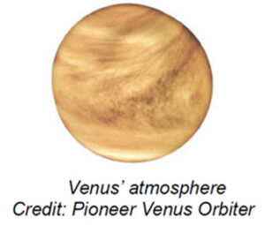 The image displays a detailed view of Venus, focusing on its swirling cloud patterns and surface features. The planet appears as a round, orange-brown sphere with intricate cloud formations. There is a prominent bright swath across the middle, indicating dense atmospheric activity. The surface is mottled with darker and lighter areas, suggesting varying terrain features or atmospheric conditions. The overall texture is smooth with visible patterns resembling turbulence or swirling formations.